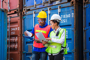 Workers in front of a shipping container discussing project finances